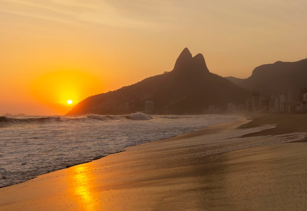 Strand von Ipanema, Brasilien bei einem Sonnenuntergang im Sommer. Two Brothers Mountain im Hintergrund mit schönen Wellen aus dem Ozean