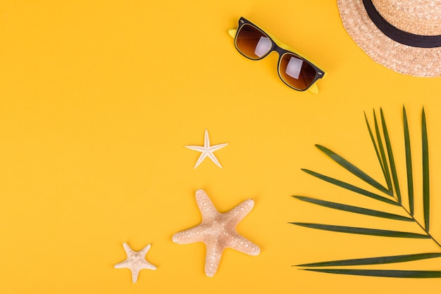 Strandaccessoires: Brille und Hut mit Muscheln und Seesternen auf farbigem Hintergrund. Sommer Hintergrund