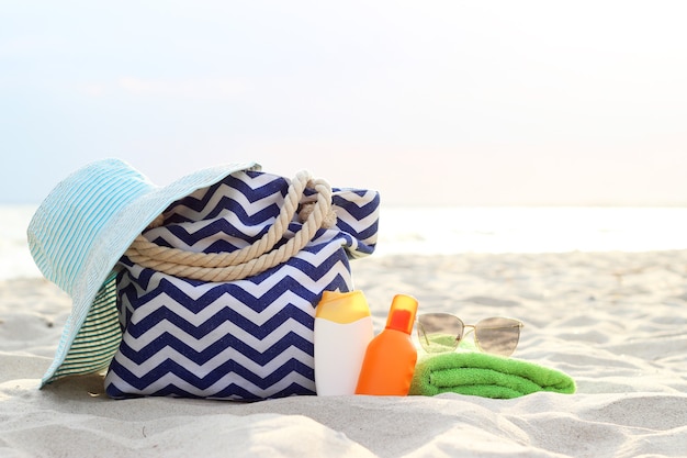 Strandaccessoires und Sonnenschutzmittel auf dem Sand des Meeres. Foto in hoher Qualität