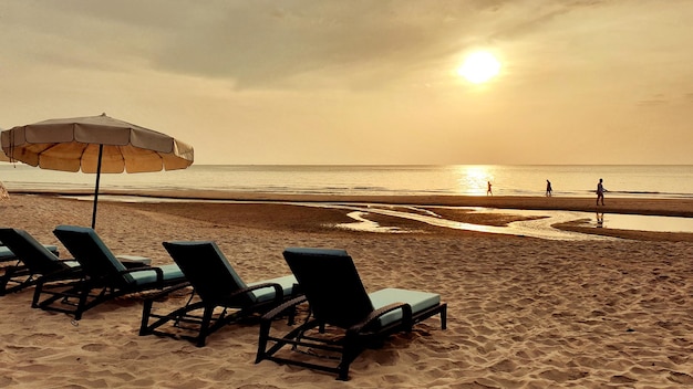 Strandbetten stehen zur schönen Sonnenaufgangszeit am Strand und am Meer.