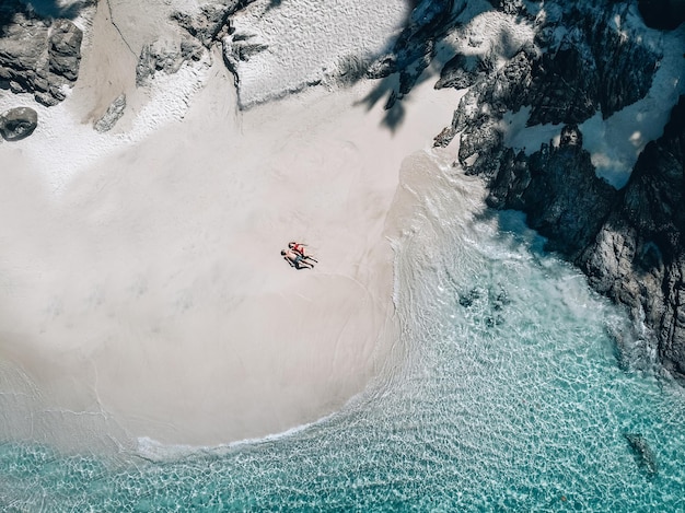 Stranddrohnenansicht Phuket tropische Insel, weißer Strand mit Wellen, Paar legte sich auf den Strand Mann und Frau. Luftbild. Reise zum warmen Ziel.