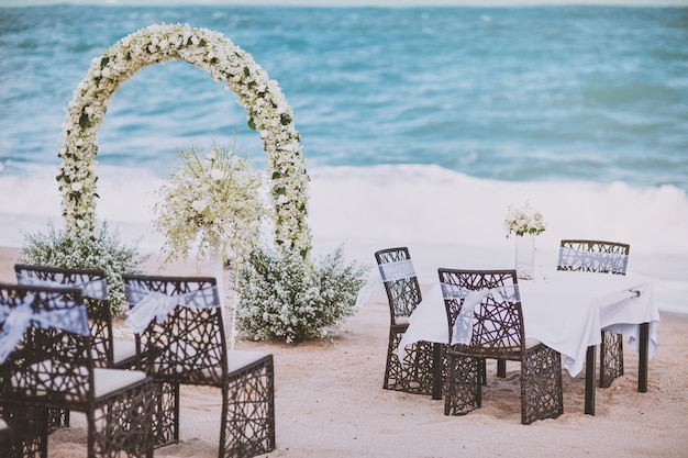 Strandhochzeits-Veranstaltungsorteinstellung mit Blumendekoration auf Bogen