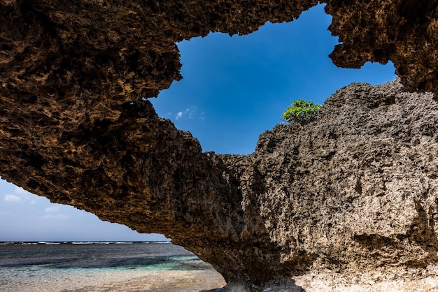 Strandhöhle in einer Felsformation blauer Himmel grüne Pflanzenwolkenansicht durch das Höhlenloch