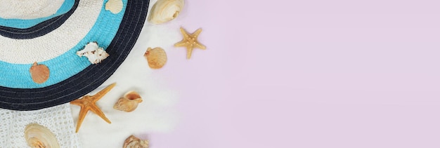 Strandhutnetz und Sand mit Muscheln auf rosa Hintergrund im sommerlichen Kopierraum