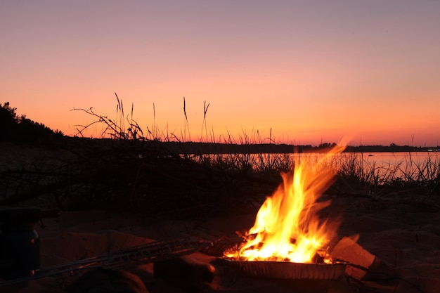 Strandlagerfeuer am See. Roter Superior-Sonnenuntergang. Abend roter Sonnenuntergang. Feuer am Strand