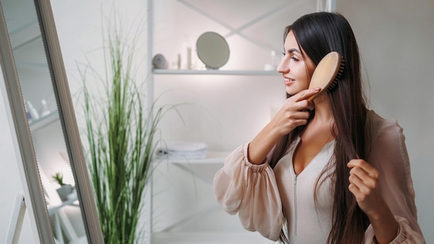 Strands beleza cuidado matinal tratamento saudável mulher muito elegante escovando cabelo brunete longo em
