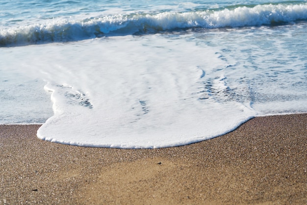 Strandsande und Welle