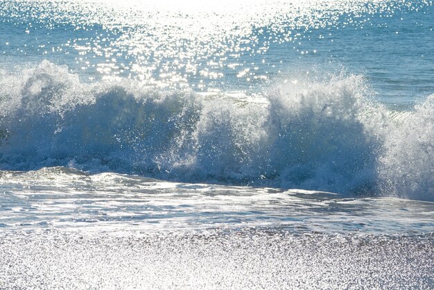 Strandsande und Welle