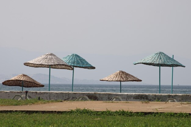 Strandschirm aus Korbgeflecht und weiße Sonnenliege aus Plastik am Strand