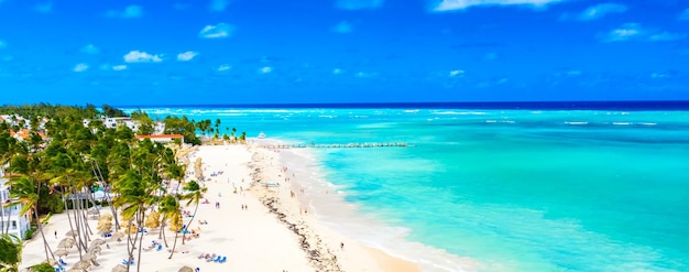 Strandurlaub. Luftdrohnenansicht des tropischen weißen Sandstrandes von Bavaro in Punta Cana, Dominikanische Republik. Erstaunliche Landschaft mit Palmen, Regenschirmen und türkisfarbenem Wasser des Atlantiks. Breites Format.