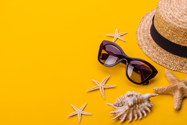 Strandzubehör: Brille und Hut mit Muscheln und Seesternen. Sommerhintergrund