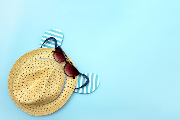 Strandzubehör Strohhut Sonnenbrille Flip Flops auf einem blauen Hintergrund Leinen Hintergrund Kopie Raum