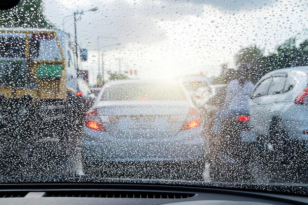Straße bei starkem Regen Wassertropfen oder Regen vor dem Spiegel des Autos auf der Straße oder Straße Fahren bei Regen Verschwommener Hintergrund