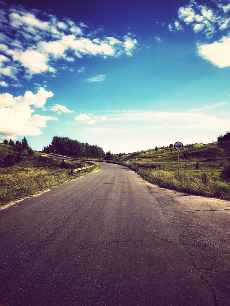 Foto straße, die durch die landschaft gegen den himmel führt