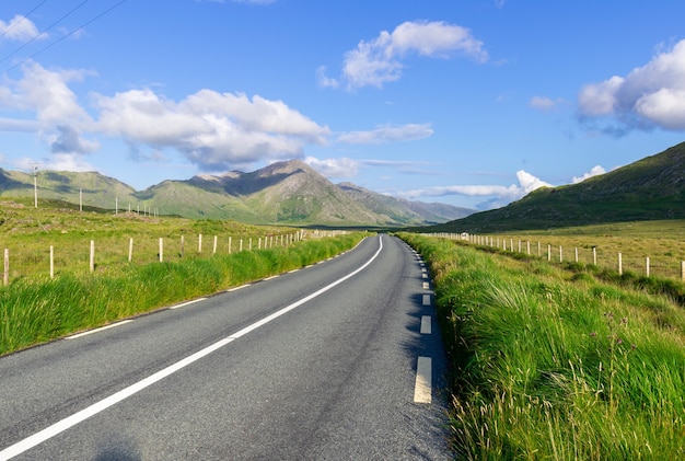 Straße in Connemara mit Blick auf die Berge am Horizont.