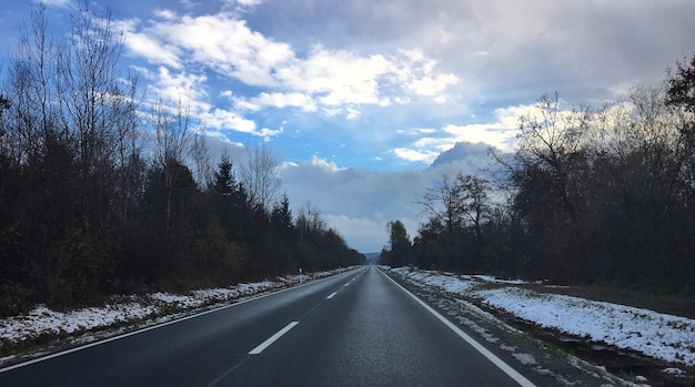 Straße inmitten der Bäume gegen den Himmel