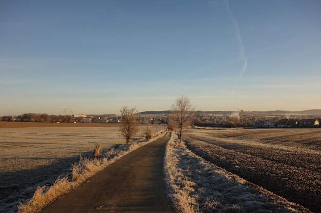 Straße inmitten des Feldes gegen den Himmel im Winter