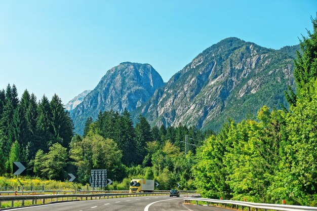 Straße mit Autos und Alpenbergen im Hintergrund. Österreich im Sommer.