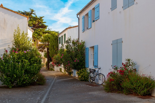 Straße mit bunten Blumen und einem klassischen Fahrrad, das an eine weiße Wand gelehnt ist