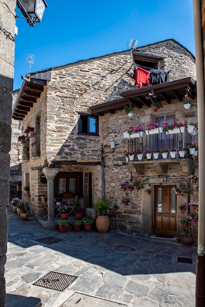 Straße mit Kopfsteinpflaster mit malerischen Wohnhäusern aus Stein und geblümten Balkonen in Puebla de Sanabria SPANIEN