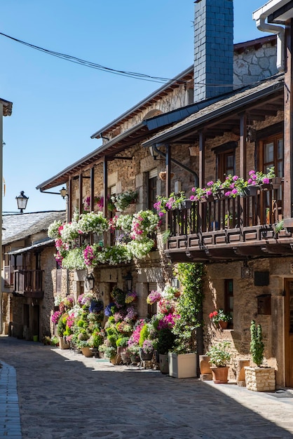 Straße mit Kopfsteinpflaster mit malerischen Wohnhäusern aus Stein und geblümten Balkonen in Puebla de Sanabria SPANIEN