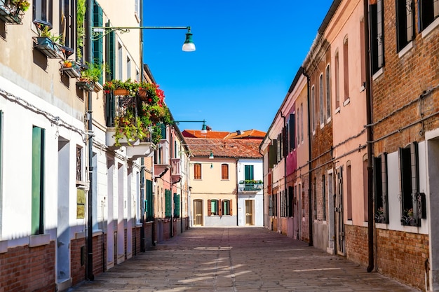 Straße von Murano mit bunten Häusern und Pflanzen in Venedig, Italien.