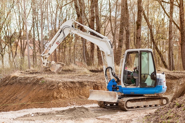 Straßenarbeiten im Park Bagger gräbt Graben Mini-Bulldozer baut Straße im öffentlichen Park