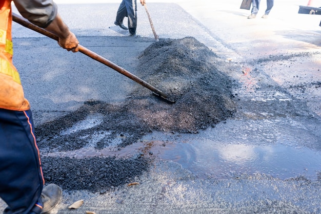 Foto straßenarbeiter, der straßenschaufeln für asphalttupfer für die arbeit herstellt