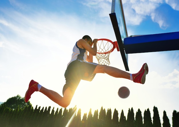 Straßenbasketballspieler, der Power-Slum-Dunk durchführt