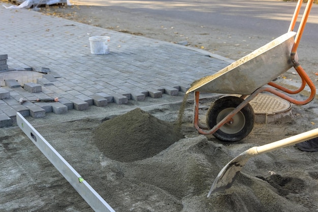 Straßenbauarbeiten an einer Straße in der Stadt mit Vorbereitung der Oberfläche, um Bürgersteigziegel aus sandigem Sandgrund zu erstellen