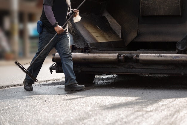 Straßenbauarbeiter, die Asphaltstraße reparieren.