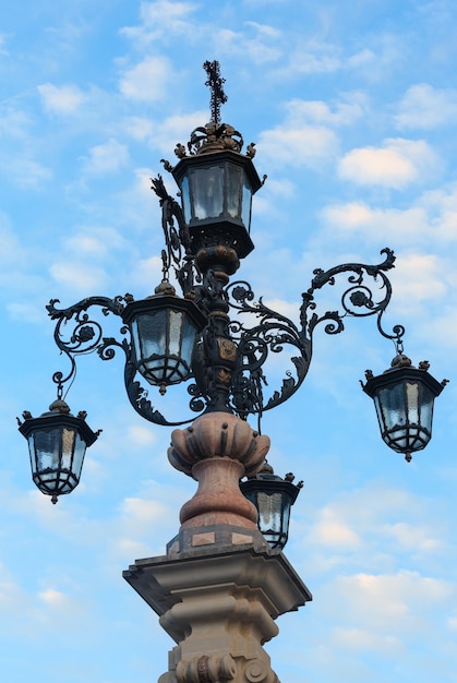 Straßenlaterne im alten Stil auf blauem Himmelshintergrund mit Wolken.