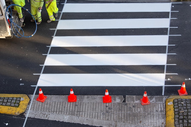 Straßenmaler, der am Zebrastreifen einer Stadtstraße arbeitet