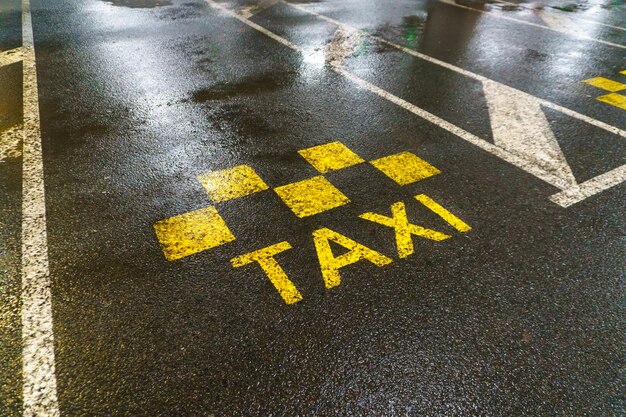 Straßenmarkierungen für Taxis Die Stelle, an der Taxis und Fahrzeuge mit festen Strecken anhalten Straßenmarkierung auf nassem Asphalt