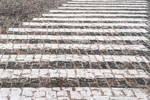 Straßenpflaster Straßenmarkierungen mit einem Fußgängerüberweg Abstrakter Hintergrund von Pflastersteinen