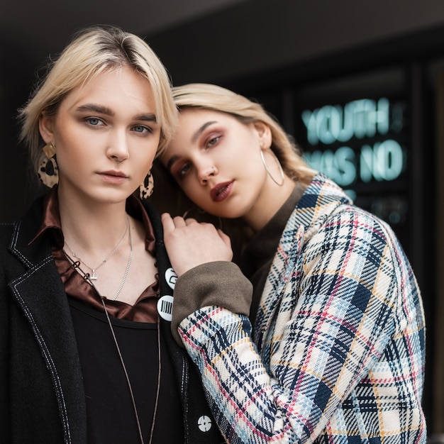 Straßenporträt junge attraktive Blondinen Schwestern Frauen in stilvollen modischen Kleidern in der Nähe der Vintage-Wand in der Stadt. Sexy Modemädchen, die draußen posieren