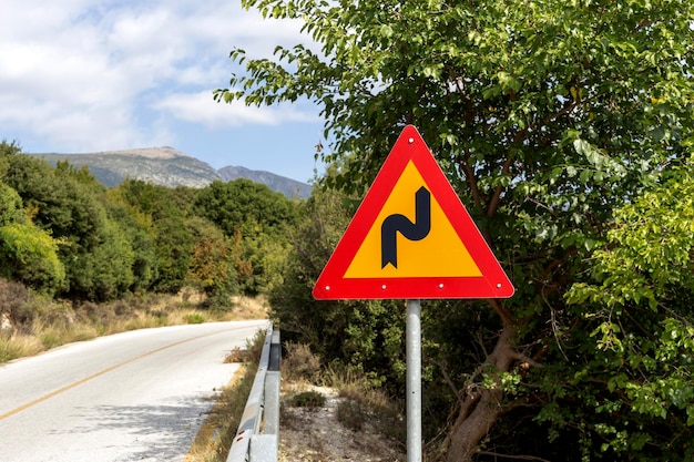 Straßenschild "Eine scharfe Kurve" auf einer Bergstraße