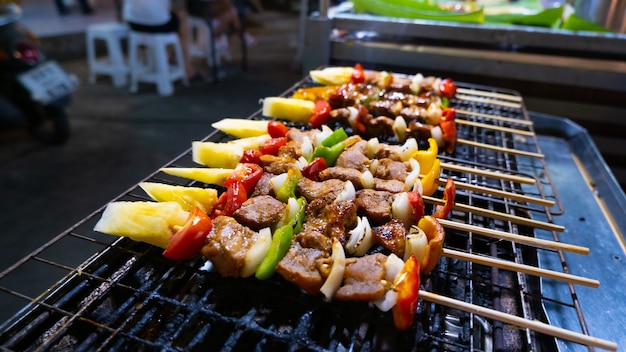 Straßenverkäufer aus nächster Nähe grillt verschiedenes BBQ-Fleisch und -Gemüse