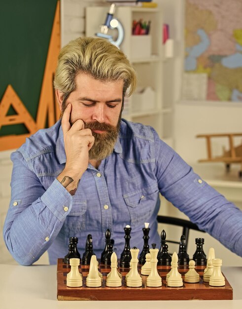 Foto strategiekonzept schullehrer brettspiel kluger mann, der schach spielt figuren auf dem schachbrett intellektuelles hobby nachdenken über den nächsten schritt machen sie ihr eigenes denken unabhängig schachstunde