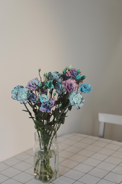 Strauß blauer und violetter Blumen in einem Glas auf dem Tisch in einem sonnigen Raum minimale Wohnkultur
