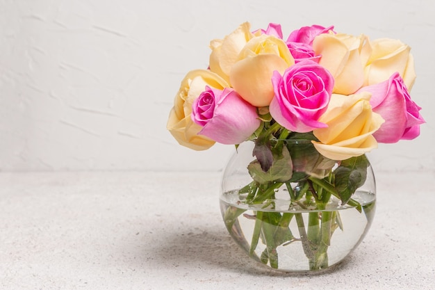 Strauß frischer mehrfarbiger Rosen in einer Vase. Das festliche Konzept für Hochzeiten, Geburtstage, 8. März, Mutter- oder Valentinstag. Grußkarte, heller Hintergrund