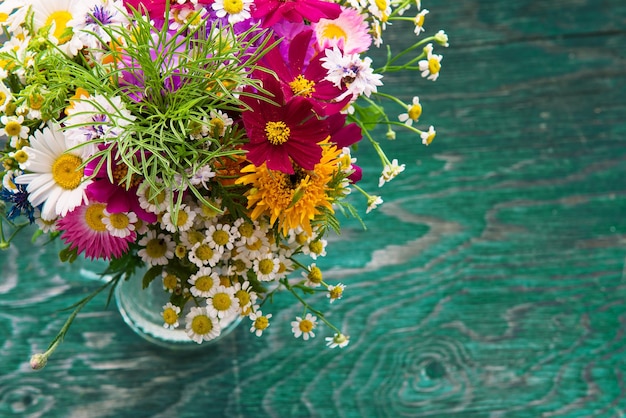 Strauß frischer Sommerblumen auf dem blauen hölzernen Grunge-Schreibtisch Mock-up für Grußkarten Urlaubspostkarten Einladung im Vintage-Hipster-Öko-rustikalen Stil mit Kopierraum