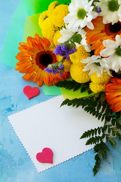 Foto strauß gerbera mit chrysanthemen mit herzen und leerer note.