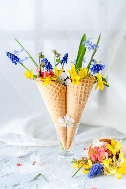 Strauß heller Frühlingsblumen in einem Waffelbecher-Hintergrundraum für Text