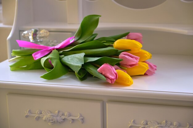 Strauß mehrfarbiger Tulpen auf dem weißen Tisch in einem hellen Raum