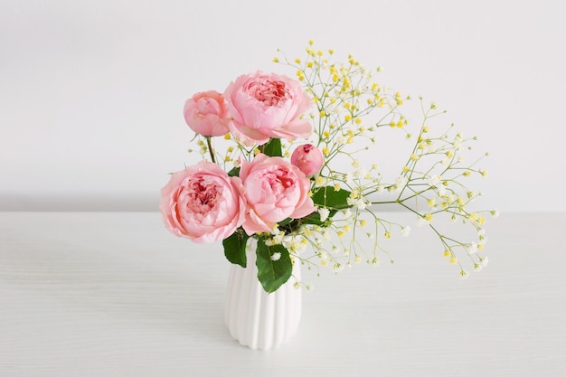 Strauß rosa Rosen in weißer Keramikvase auf weißem Hintergrund