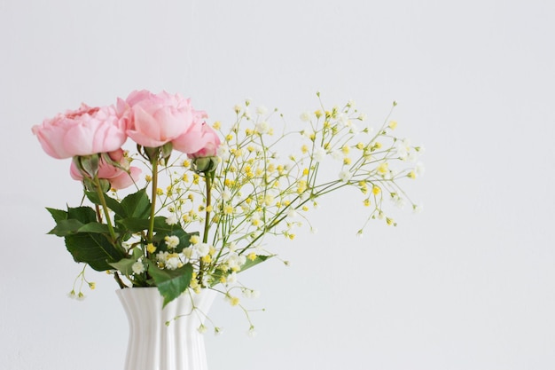 Strauß rosa Rosen in weißer Keramikvase auf weißem Hintergrund