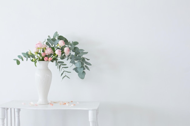 Strauß rosa Rosen in weißer Keramikvase auf weißem Vintage-Holzregal