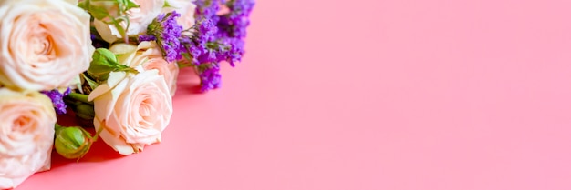 Strauß Rosen und leuchtend lila Blumen auf einem rosa Hintergrund
