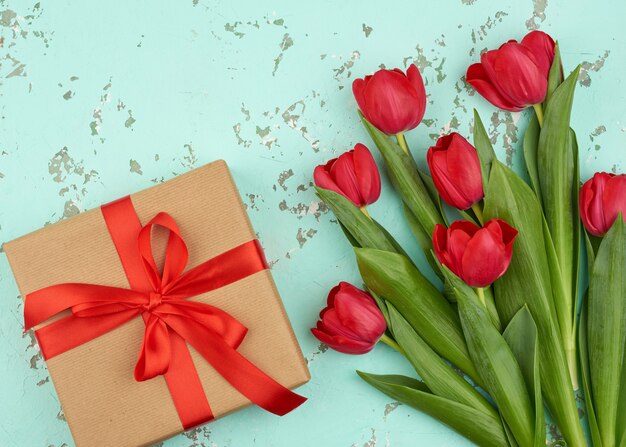 Strauß roter blühender Tulpen mit grünen Blättern, verpacktes Geschenk in braunem Bastelpapier